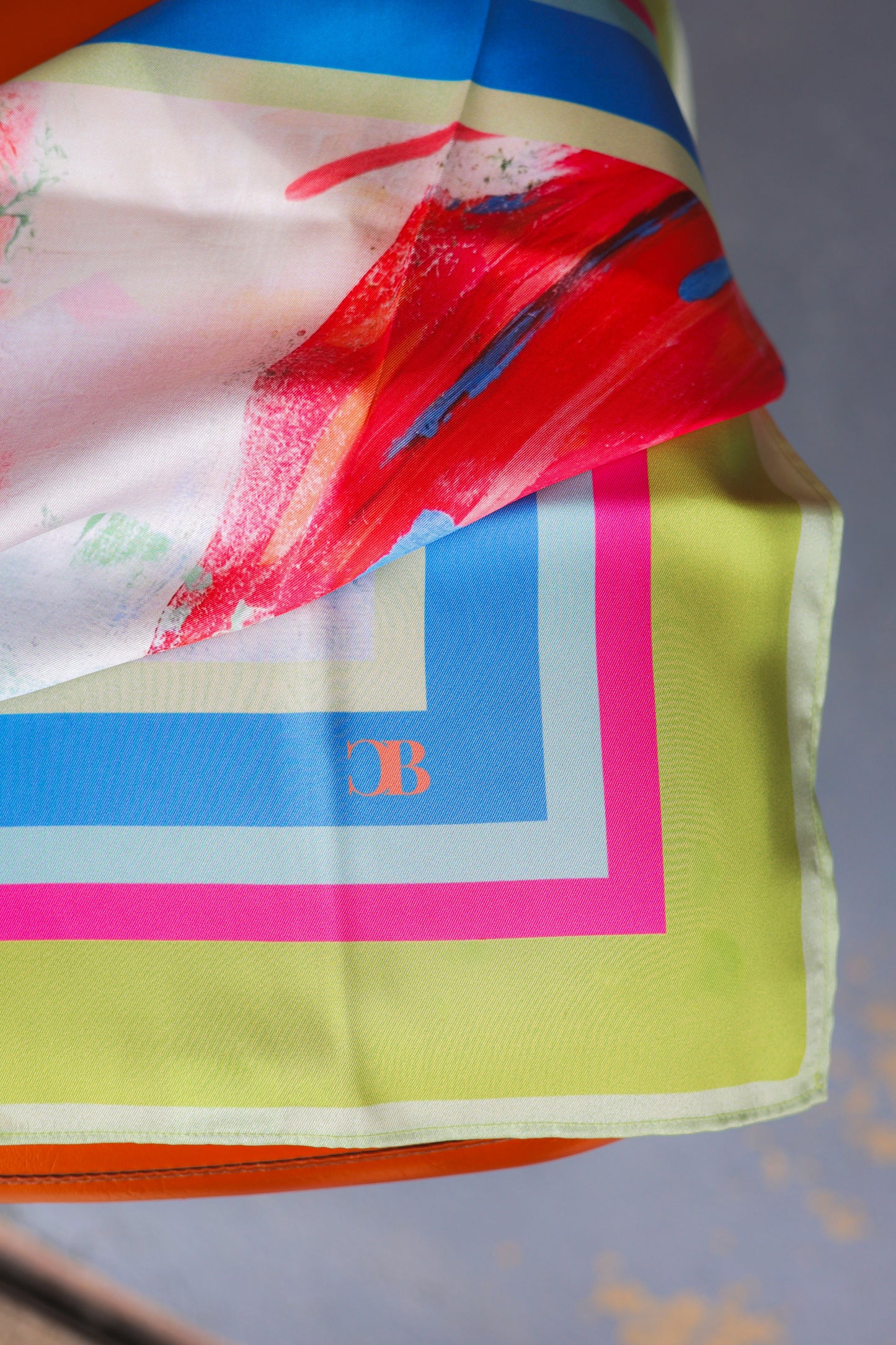 Colorful scarf with abstract design and brand logo on a gray background
