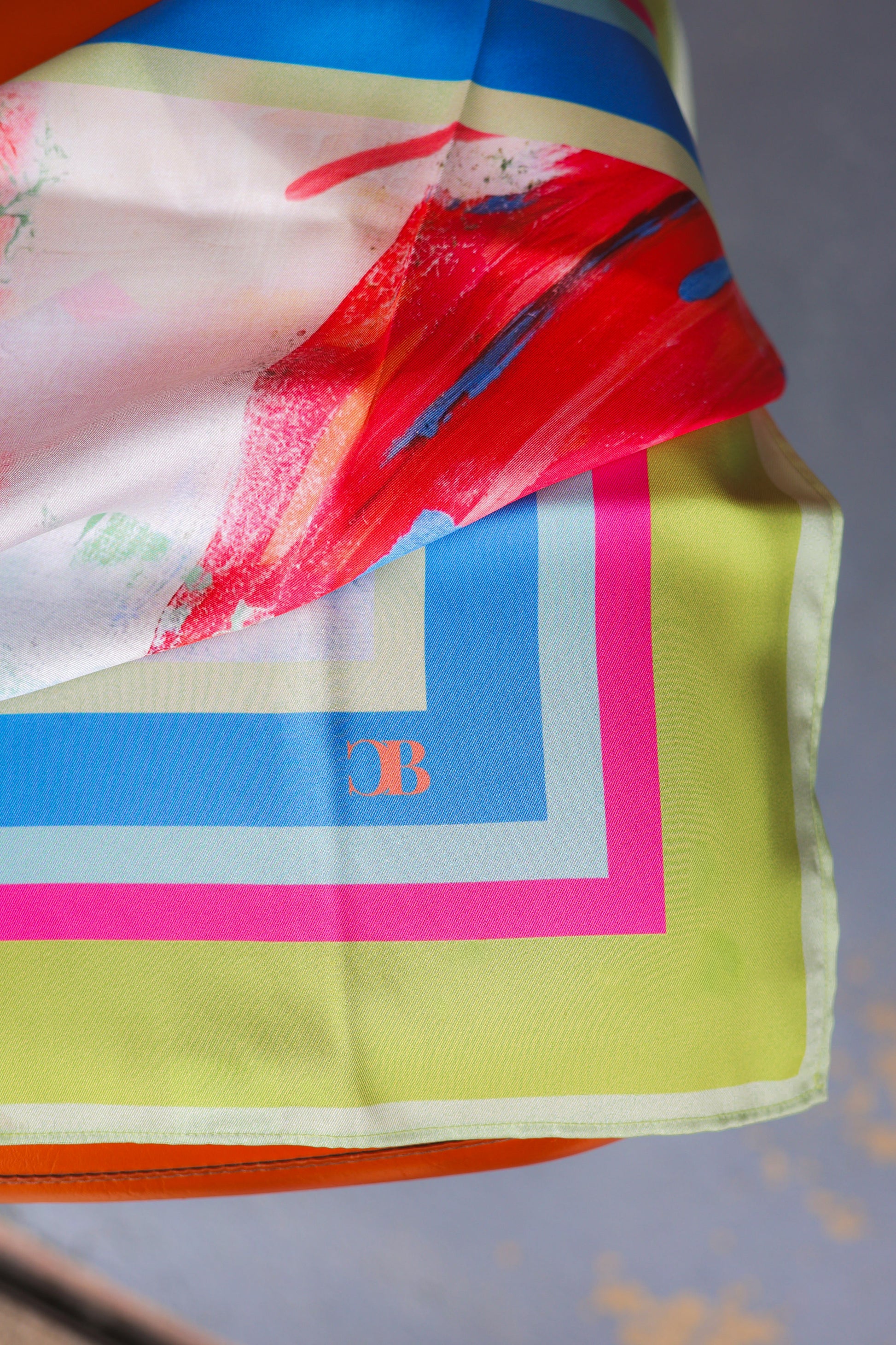 Colorful scarf with abstract design and brand logo on a gray background